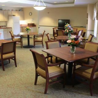 A cozy dining area with several tables and chairs, decorated with flowers on the tables.