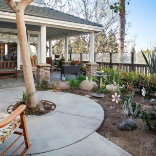 A cozy outdoor patio with a garden, featuring comfortable seating and lush landscaping.