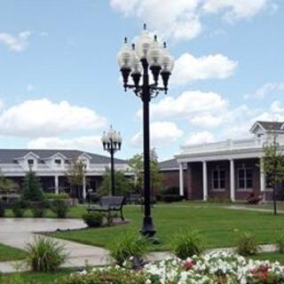 A picturesque outdoor area featuring a lamp post, benches, and garden surroundings with buildings in the background.