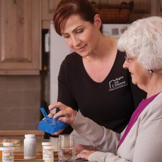 A caregiver assisting an elderly woman with medication management at home.