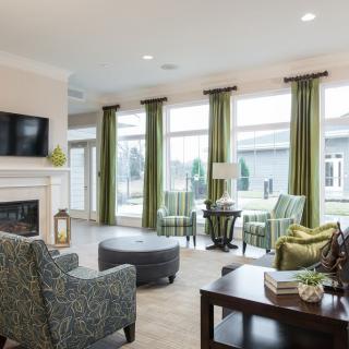 A modern living room with green curtains, comfortable seating, a fireplace, and ample natural light.