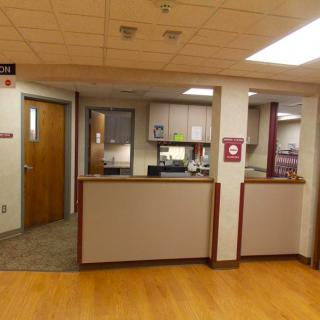 A reception area in an office with a desk and hallway.