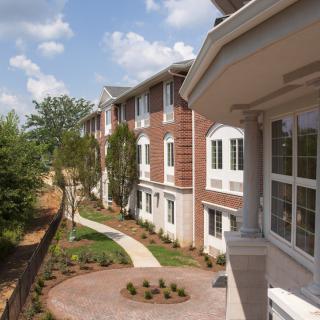 A view of a residential building with landscaped surroundings and a clear sky.