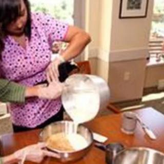 A person pouring batter into a mixing bowl while preparing a dish in the kitchen.