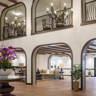 A spacious lobby with elegant chandeliers, arches, and stylish furniture.