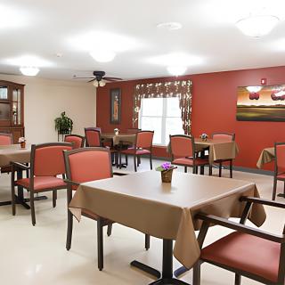A neatly arranged dining area with tables and chairs, decorated with artwork on the walls.