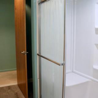 A view of a bathroom shower with a sliding glass door.