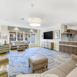 A modern living room with ample seating, a flat-screen TV, and contemporary decor.