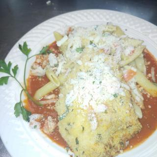 A plate of pasta topped with cheese and tomato sauce, garnished with parsley.