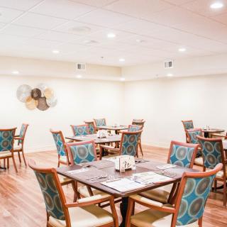A spacious dining room with neatly arranged tables and colorful chairs.
