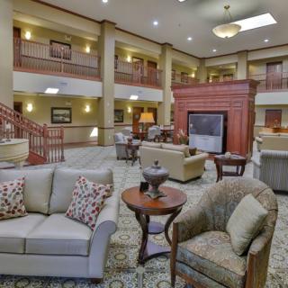 Spacious hotel lobby with comfortable seating and a central fireplace.