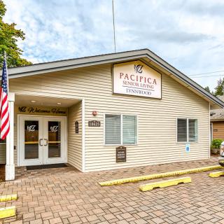 A single-story building with an entrance, displaying a sign and an American flag outside.