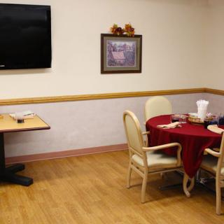 A small dining area with a round table, chairs, and a wall-mounted television.