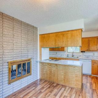 A cozy kitchen with wooden cabinets, a brick wall featuring a fireplace, and laminate flooring.