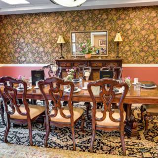 A classic dining room with elegant wooden furniture and decorative wallpaper.