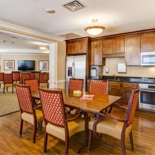 A well-furnished dining area with a wooden table and chairs, adjacent to a kitchen with wooden cabinets and modern appliances.