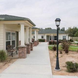 A walkway leading to residential buildings, lined with a garden and lamppost.