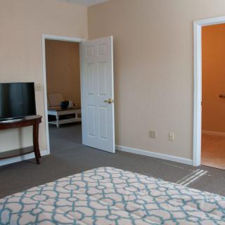 A cozy bedroom with a television, open doors, and a patterned carpet.