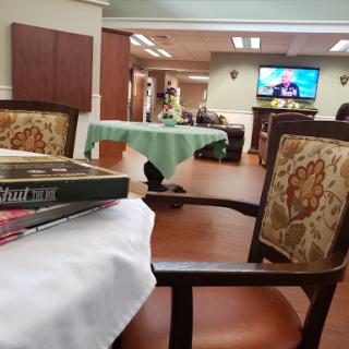 A cozy common area featuring chairs and a table, with a television in the background.