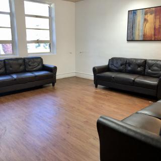 A minimalist living room with leather sofas and wooden flooring.