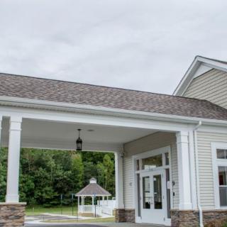 An exterior view of a building entrance with a covered porch and nearby gazebo.