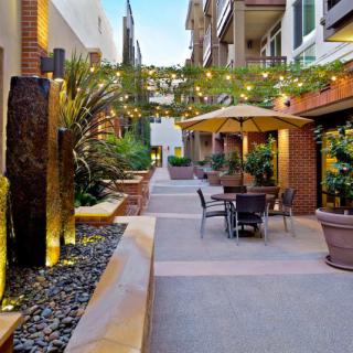 A charming outdoor patio with seating, string lights, and lush greenery in an urban environment.