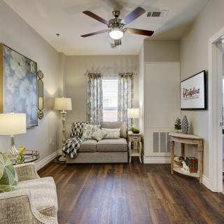 A cozy living room with modern decor, featuring a comfortable sofa, ceiling fan, and stylish artwork.