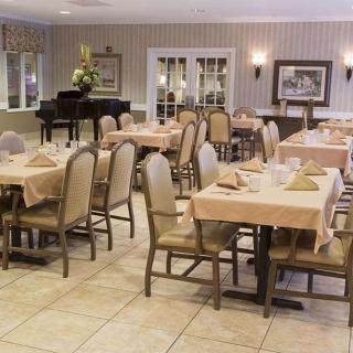 An elegant dining room with neatly arranged tables and chairs, featuring a piano in the background.