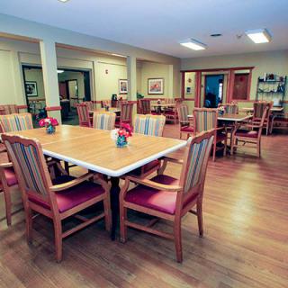 A spacious dining area featuring wooden tables and chairs, adorned with floral centerpieces.