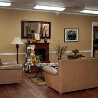 A cozy living room with sofas arranged around a central table, featuring a fireplace adorned with decorative items.