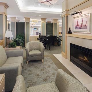 A cozy lounge area featuring comfortable seating, a fireplace, and a grand piano.