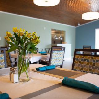 A cozy dining area with neatly arranged tables and a vase of flowers.