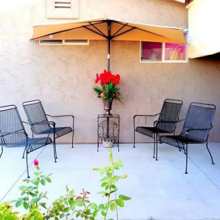 A cozy patio setup with chairs and an umbrella, adorned with flowers.