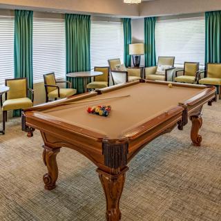 A cozy game room featuring a billiard table surrounded by comfortable seating and elegant curtains.
