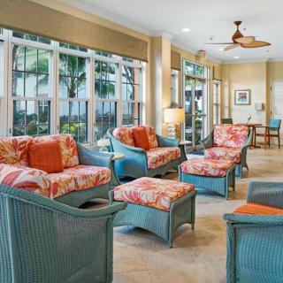 A bright and inviting living room with colorful wicker furniture and large windows.