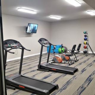 A small fitness room equipped with treadmills, dumbbells, and other exercise equipment.