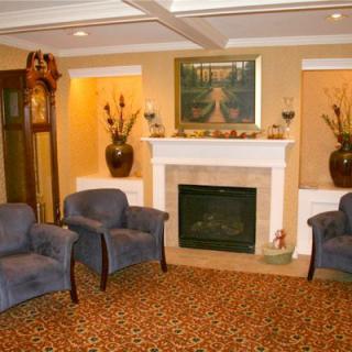 A cozy living room featuring a fireplace, armchairs, and a grandfather clock.
