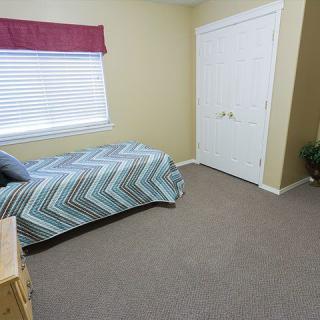 A simple bedroom with a single bed, window, and closet.