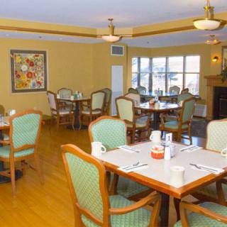 An empty dining room with neatly arranged tables and chairs, featuring warm decor and natural light.