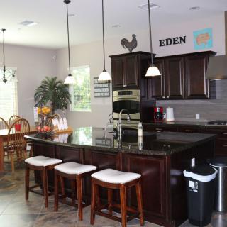 A modern kitchen with dark wood cabinets, an island with bar stools, and pendant lighting.