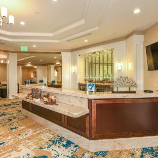 A well-lit hotel lobby with a reception desk and decorative carpet.