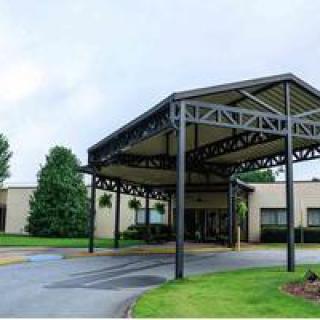 A building entrance with a large canopy and surrounding greenery.