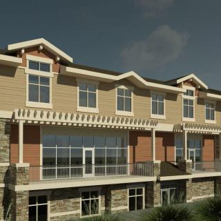 A modern residential building with large windows and balconies under a clear sky.