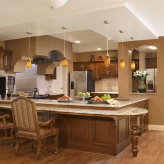 A modern kitchen with wooden cabinets, an island counter, and pendant lighting.