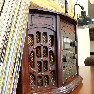 A vintage wooden radio and stereo system next to a collection of vinyl records.