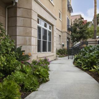 An exterior view of an apartment building with a landscaped walkway.