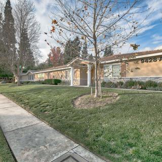 A suburban house with a manicured lawn and surrounding trees on a bright day.