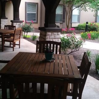 A cozy outdoor patio area featuring wooden furniture and lush garden landscaping.