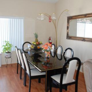 A stylish dining room with a black and white table setting, accentuated by a large mirror and indoor plants.