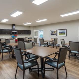 A modern dining area with tables and chairs, well-lit with overhead lights.